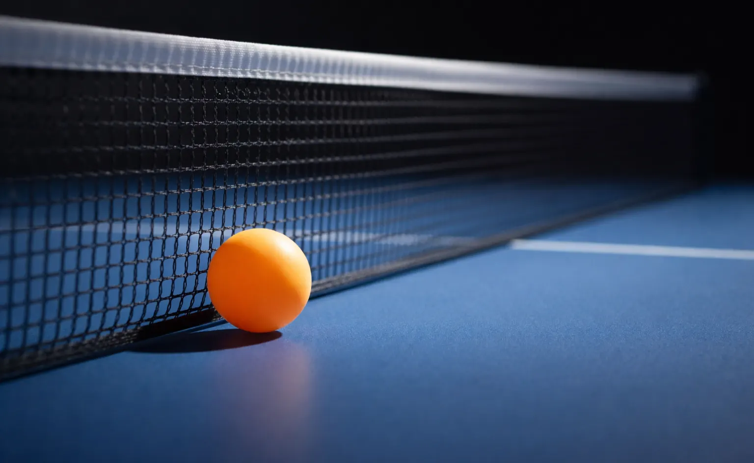 Gros plan sur un filet de tennis de table avec la balle et la raquette en arrière-plan